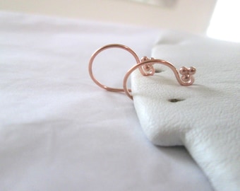 May include: A pair of rose gold hoop earrings with a small cluster of beads on one side.