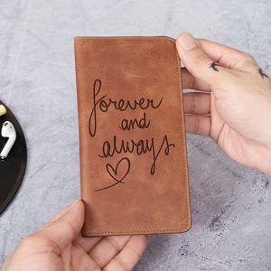 May include: A brown leather journal with the words "forever and always" and a heart engraved on the front.