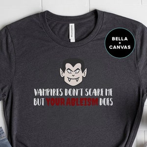 May include: A dark gray t-shirt with a graphic of a vampire and the text "Vampires don't scare me but your ableism does".