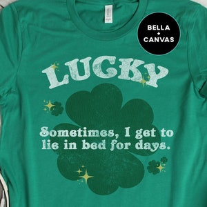 May include: Green t-shirt with a white shamrock and the text "LUCKY Sometimes, I get to lie in bed for days."