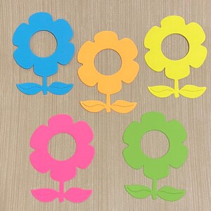 May include: Five colorful felt flower shapes with a hole in the center. The flowers are blue, orange, yellow, pink, and green.