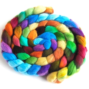 May include: A spiral of colorful wool roving in a variety of hues, including blue, green, orange, purple, and yellow. The wool is arranged in a braided pattern, creating a textured and visually appealing design. The background is plain white.