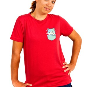 K&ouml;nnte beinhalten: Rotes T-Shirt mit einer Tasche mit einem Cartoon-Katzen-Design. Die Katze hat blaues und gr&uuml;nes Fell und schaut aus einer hellblauen Tasche heraus. Das Shirt hat eine einfarbige rote Farbe.