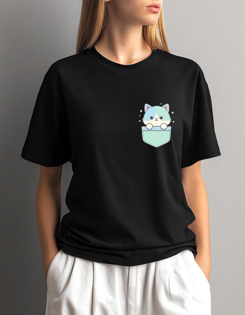 K&ouml;nnte beinhalten: Schwarzes T-Shirt mit einer Cartoon-Katze, die aus einer Tasche schaut. Die Katze hat blaues und wei&szlig;es Fell mit Sternen. Die Tasche ist hellgr&uuml;n. Das T-Shirt hat einen l&auml;ssigen Stil.
