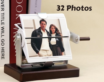 May include: A silver photo album with a wooden base and a crank handle. The album holds 32 photos and features a photo of a couple in the front.