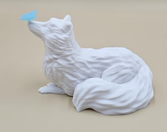 May include: A white fox figurine with a blue butterfly perched on its nose. The fox is in a resting position, with its tail curled around its body. The figurine is made of a textured material.