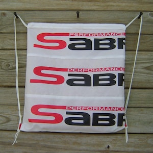 May include: White drawstring bag with three red and black "PERFORMANCE SABRE" logos printed on it.