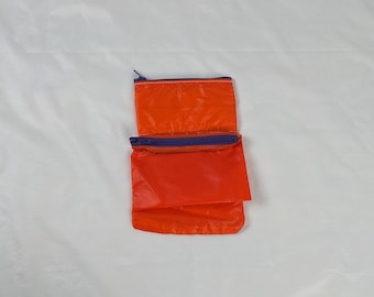 Twee zijdeachtig oranje zakjes met rits en paarse YKK-ritsen