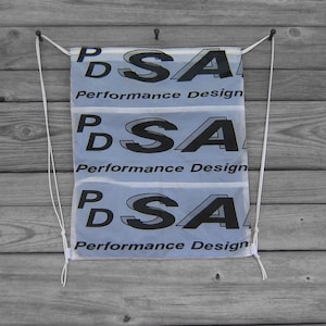 May include: Three white banners with the text "PSA Performance Design" repeated on each banner. The banners are hanging from a wooden surface with white rope.