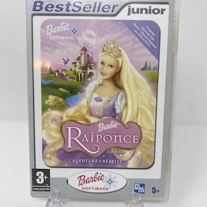 Puede incluir: Un juego de CD-ROM de Barbie Princesa Rapunzel en una caja de plástico transparente. La portada presenta a Barbie como Rapunzel con pelo largo rubio, una tiara y un castillo de fondo. El juego está clasificado para mayores de 3 años.