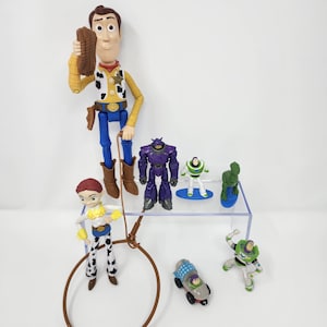K&ouml;nnte beinhalten: Eine Sammlung von Toy Story-Charakterfiguren, darunter Woody, Buzz Lightyear, Jessie und andere. Die Figuren sind farbenfroh und aus Kunststoff. Die Charaktere sind in verschiedenen Action-Posen dargestellt.