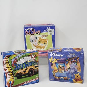 May include: Three colorful puzzle boxes: Littlest Pet Shop, Hot Wheels, and Disney Winnie the Pooh. The Hot Wheels box features a race car graphic. The Disney box shows a Winnie the Pooh scene. Each box contains 24 pieces.