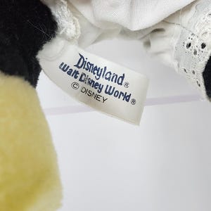 May include: A white tag with blue text that reads "Disneyland&reg; Walt Disney World&reg; &copy; DISNEY" attached to a red and white polka dot fabric.