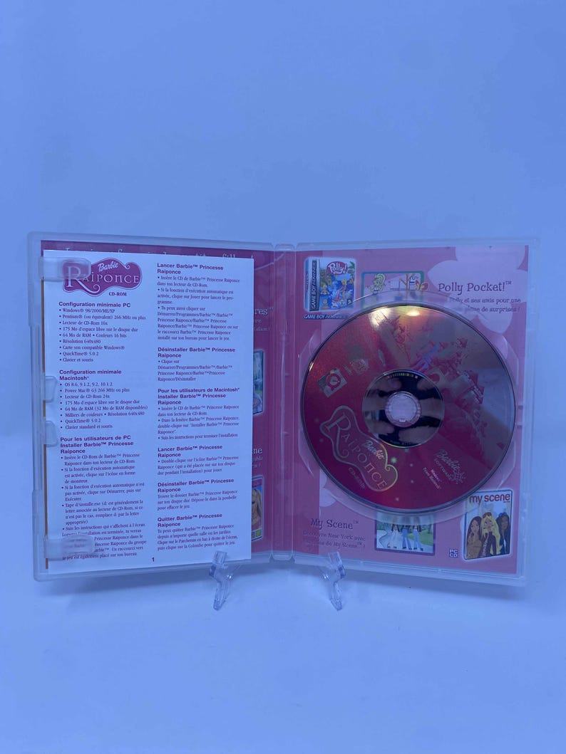 May include: A clear plastic case, open to reveal a Barbie Rapunzel CD-ROM. The CD is red and features the title "Rapunzel" and "My Scene". The case also contains printed inserts with French text.