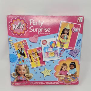 Peut inclure: Une boîte de jeu rose et bleue Kelly Party Surprise. La boîte présente des illustrations de poupées, de chapeaux de fête, de cadeaux et le texte "Party Surprise". Le jeu est pour les 3 ans et plus et 2-4 joueurs.