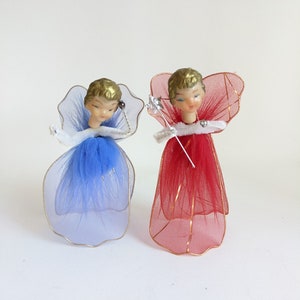 May include: Two vintage angel figurines. One angel has a blue tulle dress and wings, the other has a red tulle dress and wings. Both have gold hair and are holding a silver wand. The angels are Christmas tree ornaments.