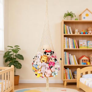 May include: A hanging macrame toy hammock filled with colorful stuffed animals. The off-white net is suspended from the ceiling, creating a decorative storage solution for a child's room. The toys include a variety of plush characters.
