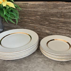 May include: A set of six white dinner plates with a gold rim and a set of six white salad plates with a gold rim.