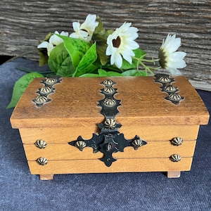 May include: A wooden treasure chest with a black metal latch and gold accents. The chest has a hinged lid and three drawers.