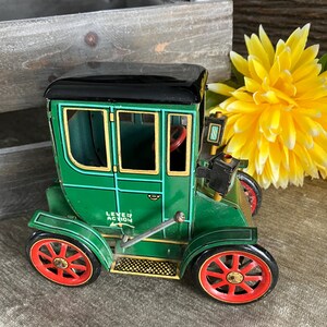 May include: A green toy car with black wheels and red accents. The car has a black roof and a lever action mechanism. The car is labelled "Lever Action" on the side.