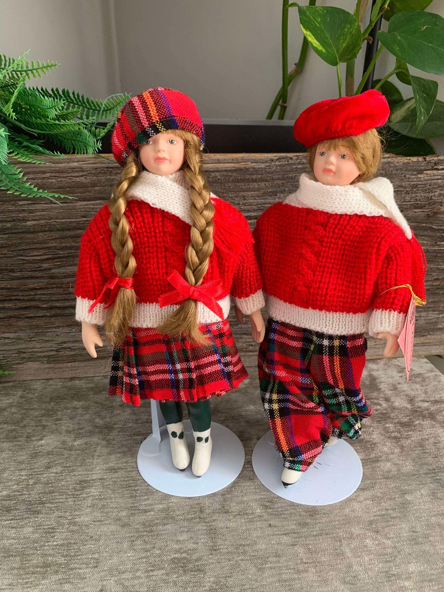 Figure Skating porcelain doll couple, male and female, red, white and black plaid clothing, winter. Dillon, show stoppers Inc(tags n stands)