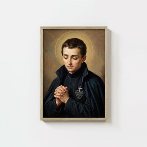 May include: A framed portrait of a man with a halo, wearing a dark blue cloak and a black jacket with a cross emblem. The man has his hands clasped in prayer. The background is a warm, golden hue.