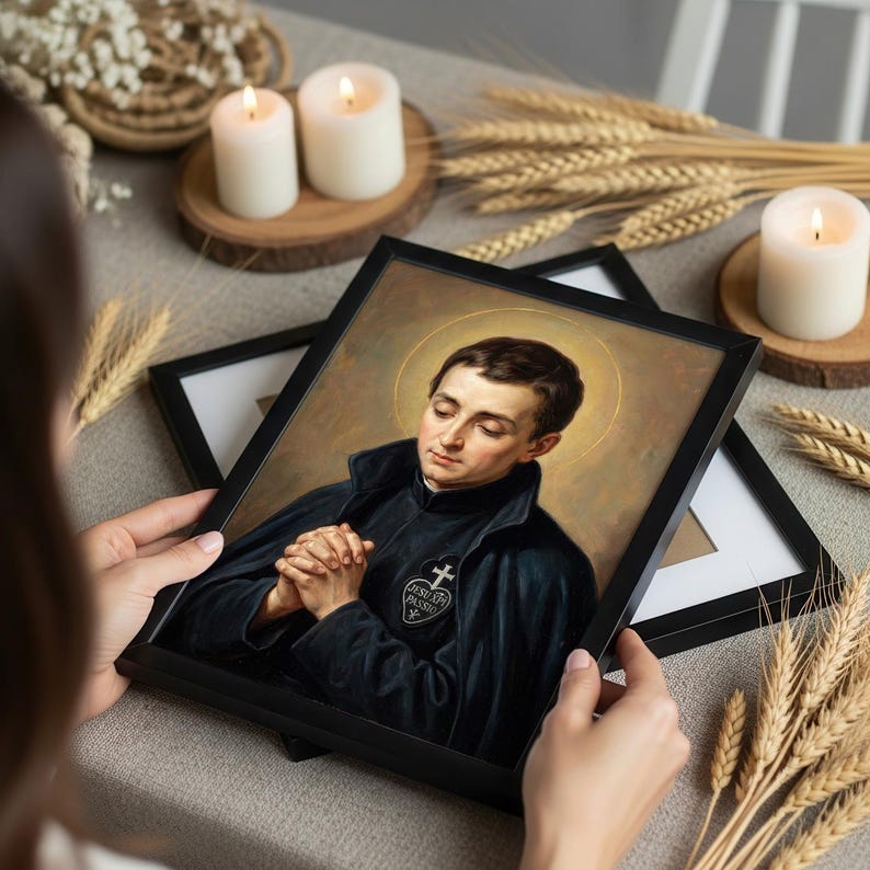 May include: A framed portrait of a man with a gold halo, wearing a black coat with a cross emblem. The portrait is held in a black frame. The image is surrounded by candles, wheat stalks, and decorative elements.