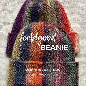 May include: Two hand-knitted beanies featuring a vertical multi-colored striped pattern in shades of purple, blue, orange, red, and green. The text "feelgood BEANIE" and "KNITTING PATTERN by yarnita.creations" is printed on the front.