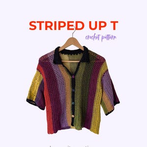 Könnte beinhalten: Ein kurzärmeliges Häkelhemd mit vertikalen Streifen in Gelb, Rot, Lila und Olivgrün. Es verfügt über einen schwarzen Kragen, eine Knopfleiste mit bunten Knöpfen und den Text STRIPED UP T crochet pattern by yarnita.creations.