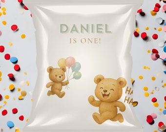 May include: A white party favor bag with the text "DANIEL IS ONE!" in light green. Two cartoon teddy bears are featured, one holding balloons and the other running with a smiling face. The words "HA HA" are printed on the bag.