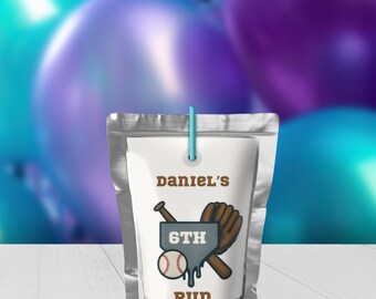 May include: A silver pouch with a white label featuring baseball graphics. The label reads "Daniel's 6th Run" with a baseball, bat, and glove illustration. A blue straw is attached to the pouch. Blue and purple balloons are in the background.