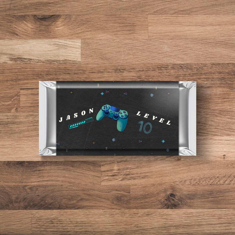 May include: A black chocolate bar wrapper with a silver foil border. The wrapper has a blue and green video game controller graphic, a progress bar with the text "JASON" and the text "LEVEL 10".