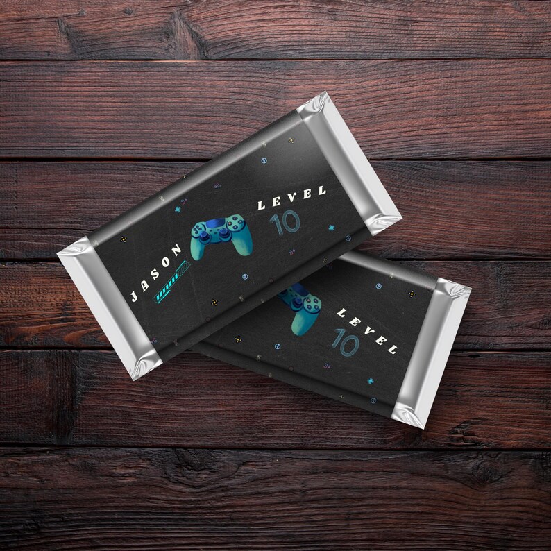 May include: Two black chocolate bar wrappers with silver foil. The wrappers have a black and white design with a blue video game controller and the text "Level 10". One wrapper has the name "Jason" on it.