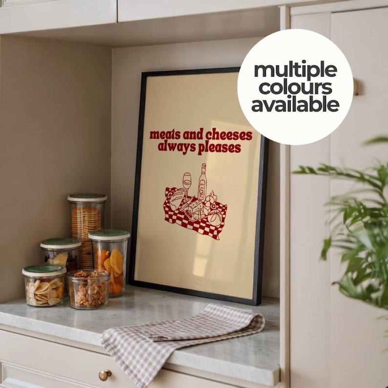 Framed retro kitchen print with bold red typography 'meats and cheeses always pleases' and a charcuterie basket illustration.