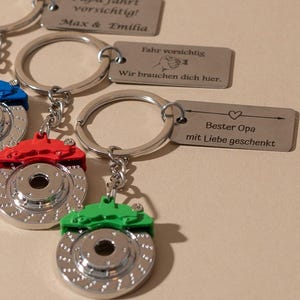 Peut inclure: Porte-clés avec des breloques en forme de rotor de frein argentés et des étriers colorés en bleu, rouge et vert. Chaque porte-clés a un anneau et une chaîne argentés. Certains porte-clés ont des étiquettes gravées avec du texte allemand.