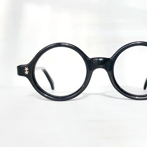 May include: Black round-framed eyeglasses with silver accents on the temples.