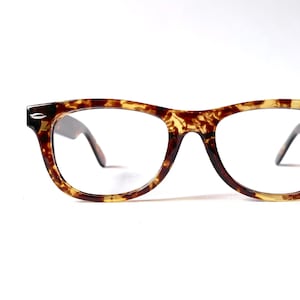 May include: Tortoiseshell eyeglasses with clear lenses. The glasses have a classic, retro style.