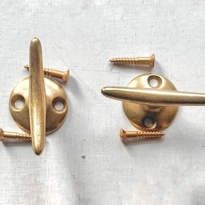 May include: A white ceramic mug with a black handle and the text "But First, Coffee" in a handwritten style. The mug is on a white surface. The mug is approximately 10 cm tall.