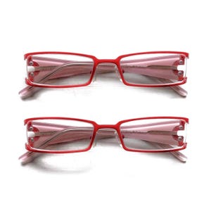 以下が含まれることがあります： 長方形のレンズが付いた赤いフレームのメガネが2組。 フレームは明るい赤色で、レンズには薄いピンクの色合いがあります。 テンプルは薄いピンク色です。