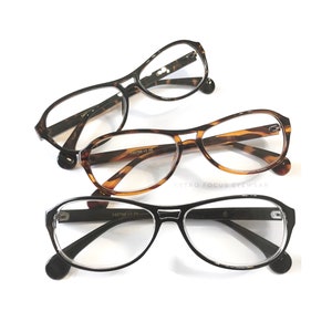 Könnte beinhalten: Drei Brillenpaare in Schildpatt- und Schwarz mit klaren Gläsern. Die Brillen sind in Dreiecksform auf weißem Hintergrund angeordnet. Der Text "RETRO FOCUS EYEWEAR" ist unten in der Mitte des Bildes sichtbar.