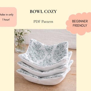May include: A stack of three bowl cozies with a white and green floral pattern. The cozies are square-shaped with curved edges and are made of fabric. Text on the image reads "BOWL COZY PDF Pattern" and "Make in only 1 hour!" and "BEGINNER FRIENDLY".