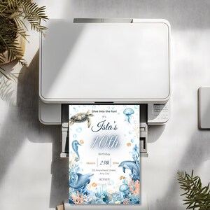 May include: A white printer printing a birthday invitation. The invitation features an underwater theme with a turtle, seahorse, dolphin, and jellyfish. Text on the invitation reads "Dive into the fun! It's Isla's 10th Birthday March 25th 3PM."