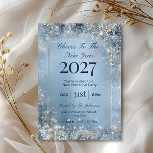 Elegant Cheers To The New Year 2027 invitation on ivory satin with dried gold florals, silver glitter and a gold frame