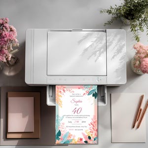 Printed spring floral birthday invitation template coming out of a printer, pastel botanical border with editable text design