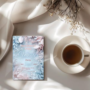 May include: A winter party invitation with a blue and pink floral design, featuring the text "Your Invited To A Cozy Winter Party". A cup of tea on a white saucer is next to the invitation. Delicate white flowers are arranged on the right.