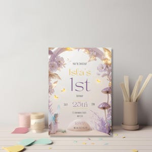 Printable fairy first birthday invitation template displayed standing upright in clean white desk styled scene with stationery showing purple fairy mushroom floral arch design