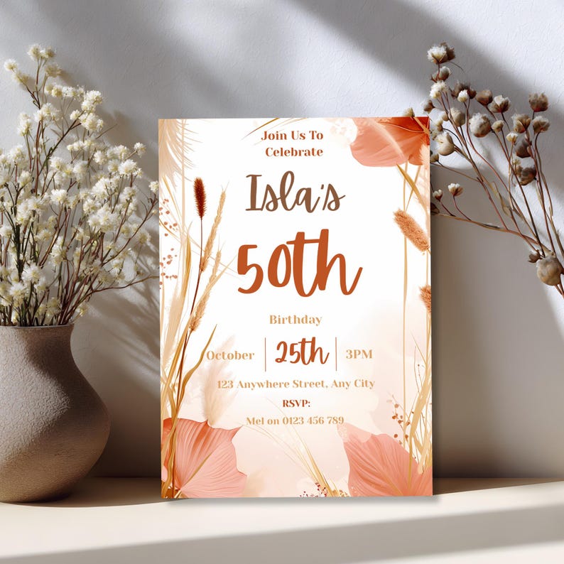 Boho terracotta 50th birthday invitation card leaning against a wall beside a vase of dried flowers