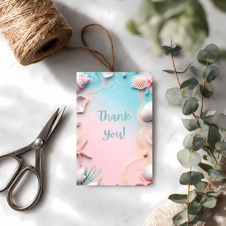 May include: A rectangular gift tag with a beach-themed design. The tag features seashells, starfish, and the words "Thank you!" against a pastel pink and blue background. A roll of twine and scissors are visible.