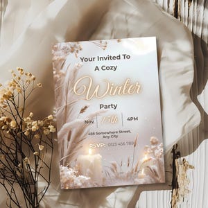 Elegant candlelit winter invitation styled among warm dried florals and soft fabric