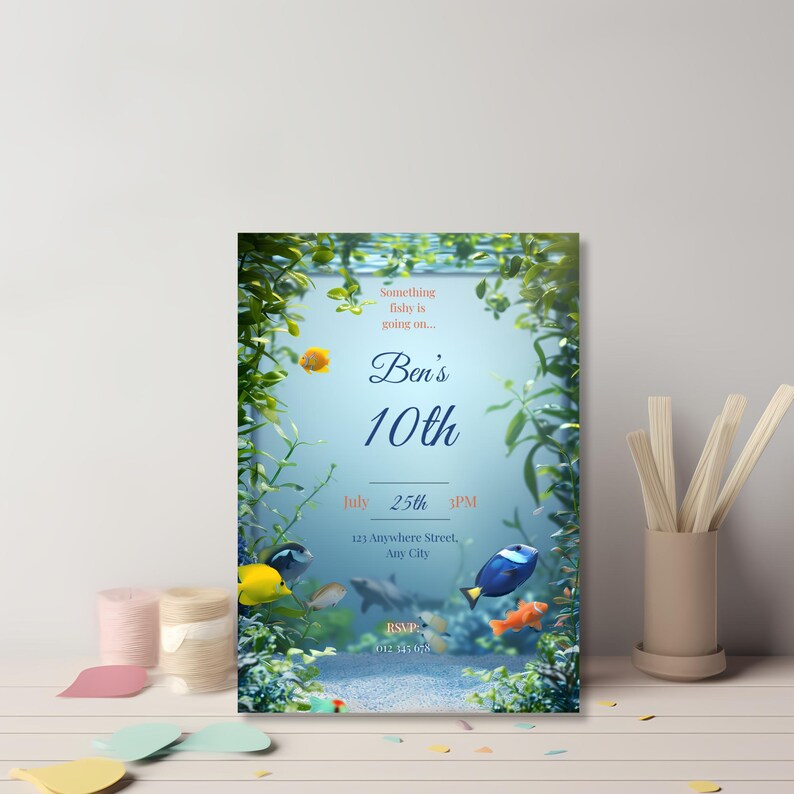 Fish-themed birthday invitation displayed on a decorated kids party table with ocean colours and props